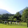 TaiChi im Garten, © Daniel Fischer Gruppe von Menschen macht Tai Chi auf einer Wiese vor Bergkulisse.