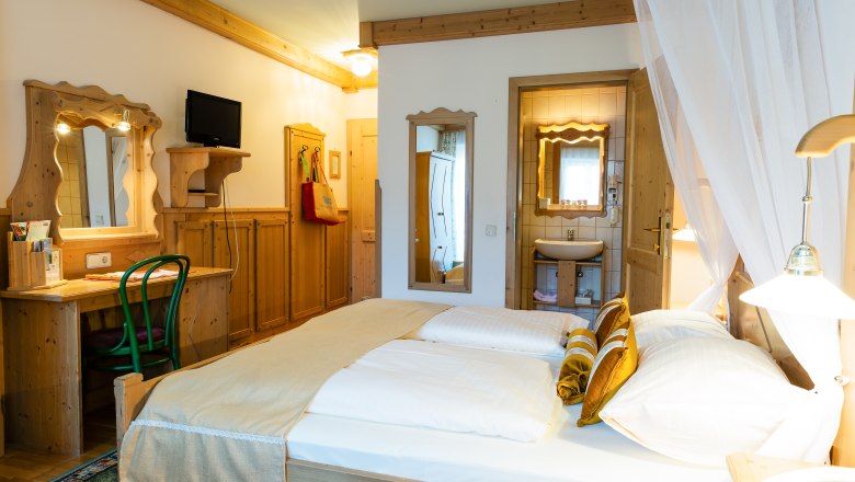Doppelzimmer Kat. C, © Scharfegger´s Raxalpen Resort Gemütliches Hotelzimmer mit Doppelbett, Holzmöbeln und kleinem Badezimmer.