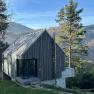 Caspar´s Home, © Meinrad Hofer Modernes Holzhaus in bergiger Landschaft mit Bäumen und blauem Himmel.