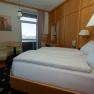 Doppelzimmer, © Sporthotel Semmering Ein gemütliches Doppelzimmer mit Holzmöbeln, einem Doppelbett, einer Sitzecke und einem Balkon mit Bergblick.