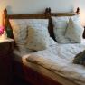 Doppelzimmer, © Reinhard Maurer Gemütliches Doppelzimmer mit Holzmöbeln, Bett mit kariertem Bettzeug, Nachttischen und Lampen.