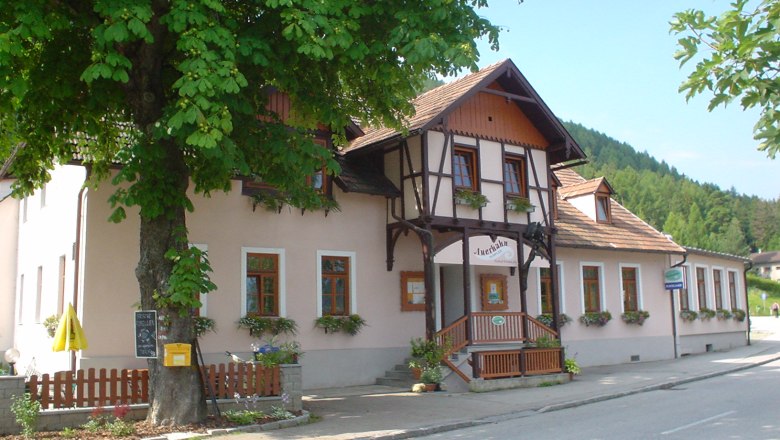 Gasthaus Auerhahn, © Marktgemeinde Schottwien Traditionelles Gasthaus, davor Blumenkästen, umgeben von Bäumen.