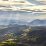 Rax Ausblick, © Wiener Alpen - Croy Panoramablick auf die Rax-Alpen mit bewaldeten Hügeln und Sonnenstrahlen durch Wolken.