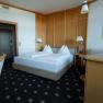 Doppelzimmer, © Sporthotel Semmering Ein Hotelzimmer mit Doppelbett, Holzmöbeln und einem Fernseher.
