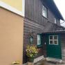 Eingang Privatzimmer Familie Jansch, © Wiener Alpen Eingang eines traditionellen Hauses mit Holzverkleidung und grünem Türrahmen.
