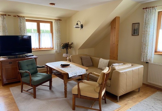 Ein Doppelzimmer mit Sitzgarnitur, © Wiener Alpen Gemütliches Wohnzimmer mit Sofa, Sesseln und Fernseher.