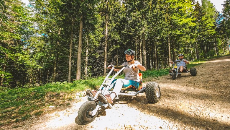 Mountaincarts Semmering, © Semmering Hirschenkogel Zwei Personen fahren mit Mountaincarts auf einem Waldweg.
