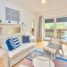 Top 2 - Wohnzimmer, © VP FeWo OG Modernes Wohnzimmer mit Sofa, Kissen, Glastisch und Balkon.