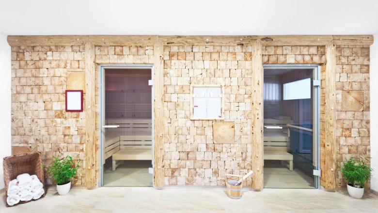 Wellnessbereich, © Hotel Payerbacherhof Zwei Saunakabinen mit Holzwänden und Glastüren in einem Wellnessbereich.