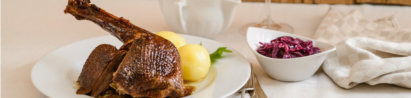 Schmankerl abholen und zu Hause genießen, wie zum Beispiel das traditionelle Martini Gansl, © Wirtshauskultur Niederösterreich Nahaufnahme von einem Martinigansl mit Knödel und einem Schüsserl Rotkraut