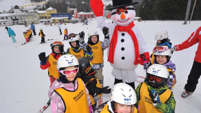 Happylift Semmering, © Josef Latzelsperger Kinder in Skiausrüstung posieren mit einem Schneemann auf einer Skipiste.