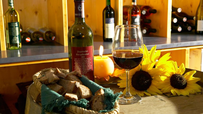 Vinodukt, © Vinodukt, Foto: Franz Zwickl Weinflasche und Glas auf einem Fass mit Brot und Sonnenblumen.