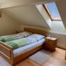 Doppelzimmer Jansch, © Wiener Alpen Gemütliches Doppelzimmer mit Dachfenster, Holzbett und Nachttisch.