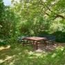 Garten, © VP FeWo OG Ein ruhiger Garten mit zwei Bänken und einem Tisch unter einem großen Baum.