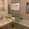 Badezimmer, © Wiener Alpen Modernes Badezimmer mit Waschbecken, Spiegel, Badewanne und Handtüchern.