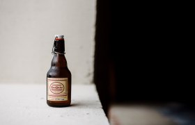 Raxbräu, © NÖW/Maria Hohla Eine Flasche RaxBräu Helles Bier auf einer weißen Oberfläche vor einem dunklen Hintergrund.