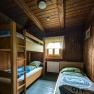 Karl-Ludwig-Haus - Dreibettzimmer, © Kai Weidinger Holzvertäfeltes Dreibettzimmer mit Etagenbett und Einzelbett, Fenster mit Vorhang, rustikale Einrichtung.
