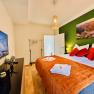 Joes Coxy Apartment, © Brunner Gemütliches Schlafzimmer mit grünem Akzent, Doppelbett, TV und Dekoration.