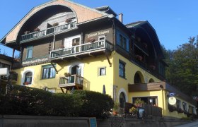 Hotel Belvedere, © Hotel Belvedere Ein traditionelles Hotel mit gelber Fassade und Holzbalkonen, dekoriert mit Blumen.