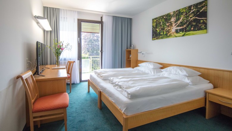 Zimmer im Parkhotel Hirschwang, © Friedl & Partner Hotelzimmer mit Doppelbett, Schreibtisch, Stuhl und Balkon.