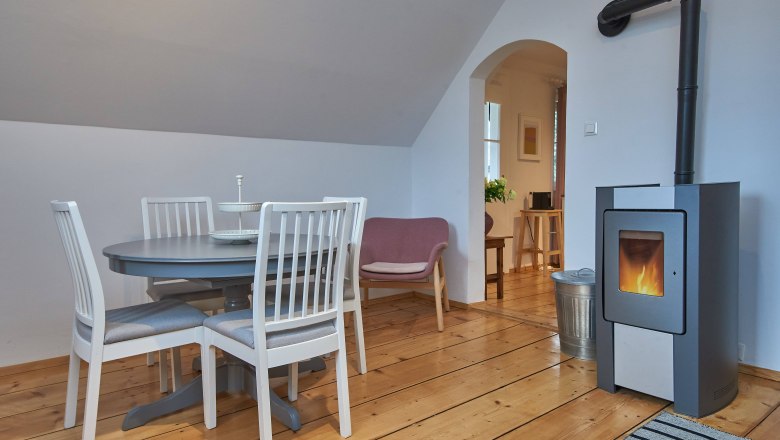 Top 2 - Wohnzimmer, © VP FeWo OG Gemütliches Wohnzimmer mit Esstisch, Stühlen, Sessel und Kamin.