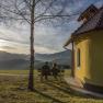 Kapelle - Ramswirt, © Gasthof Ramswirt Zwei Personen sitzen auf einer Bank neben einer kleinen Kapelle mit Blick auf die Berge bei Sonnenuntergang.