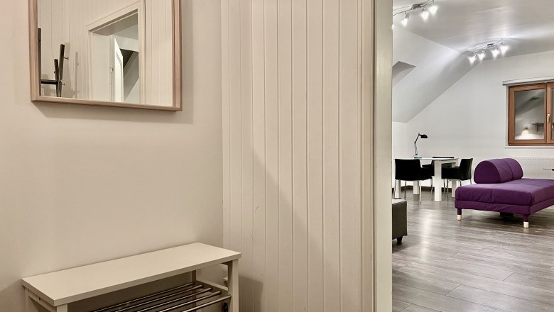 Loft am Hauptplatz, © Relax Apartments Innenansicht eines modernen Lofts mit lila Sofa und Esstisch.