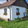 Leo-Hof Ferienwohnung Kathi, © Leo-Hof/Sandra Reinisch Weißes Haus mit roten Blumen in Blumenkästen vor den Fenstern, grüne Wiese im Vordergrund.