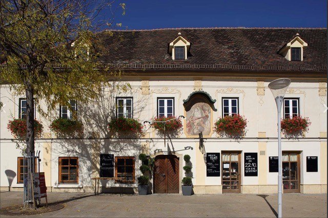 S Platzl außen, © Schilowsky_NM_©redtenbacher Historisches Gebäude mit Blumenkästen und Wandgemälde.