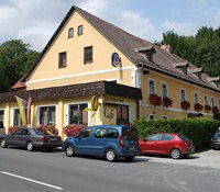 Gasthof Oberer Eggl, © WVAP Perner, Foto Franz Perner Ein gelbes Gasthaus mit roten Blumen und parkenden Autos davor.