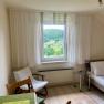Schlafzimmer2(c)wieneralpen, © Wiener Alpen Helles Schlafzimmer mit Fensterblick auf grüne Landschaft, Bett, Stuhl und Tisch.