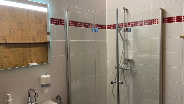 Badezimmer mit Dusche und WC, © Wiener Alpen Modernes Badezimmer mit Dusche, Waschbecken und Spiegel.