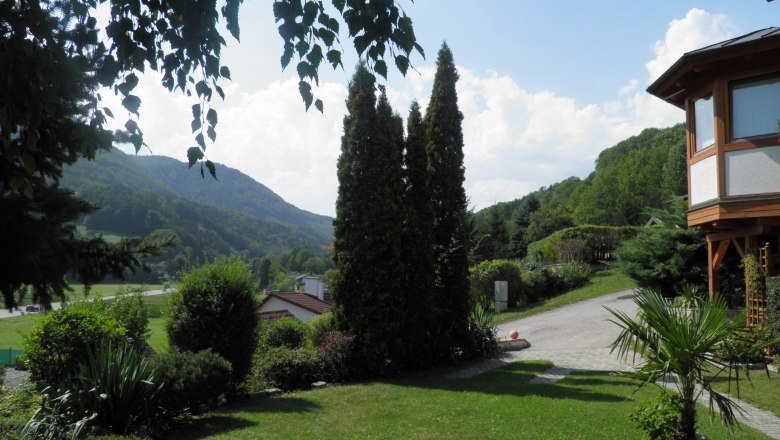 Aussicht, © Kesper Garten mit Bäumen und Blick auf bewaldete Hügel im Hintergrund.