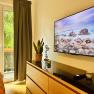 Joes Coxy Apartment, © Brunner Gemütliches Zimmer mit TV, Kommode, Pflanze und Balkonblick.