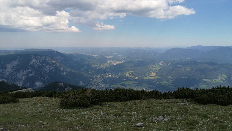 Jakobskogel auf der Rax, © Wiener Alpen Blick vom Jakobskogel auf der Rax über eine weite Berglandschaft mit Tälern und Wäldern unter einem bewölkten Himmel.