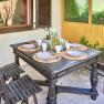 Top 1 - Terrasse, © VP FeWo OG Gedeckter Tisch auf einer Terrasse mit vier Plätzen, Holzmöbeln und Pflanzen im Hintergrund.