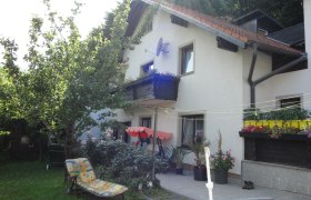Privatzimmer Gulnbrein, © Privatzimmer Gulnbrein Ein Haus mit Garten, Liegestuhl und Blumen auf der Terrasse.