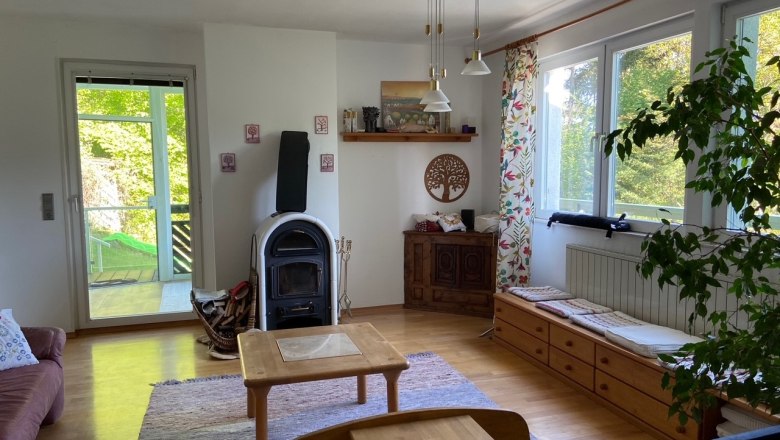 Wohnzimmer, © Wiener Alpen Ein gemütliches Wohnzimmer mit Holzofen, Holzmöbeln und großen Fenstern mit Blick ins Grüne.