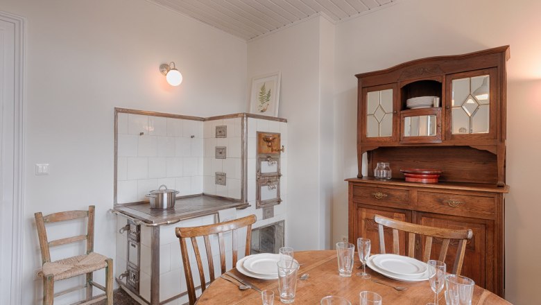 Top 3 - Küche, © VP FeWo OG Vintage Küche mit Holzschrank, altem Herd und gedecktem Tisch.