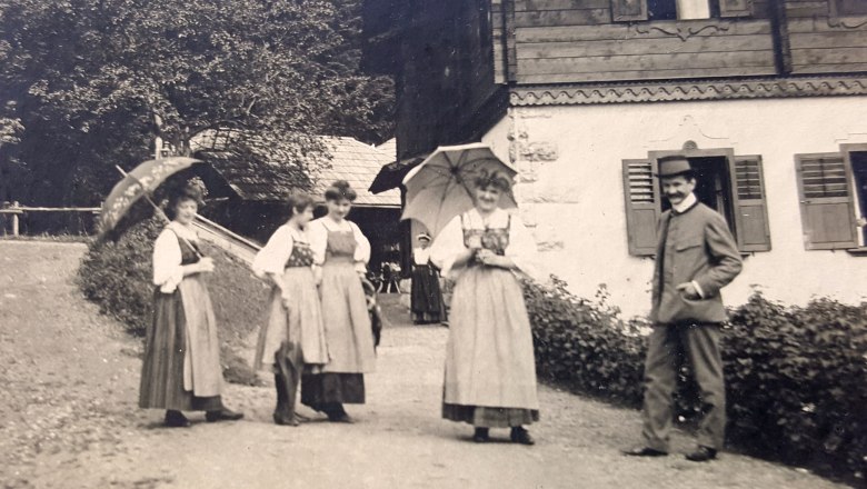 Riegelhof historisch, © Riegelhof Schwarz-weiß Bild mit Frauen in langen Kleidern und rechts davon ein Mann mit Jagdanzug und Hut