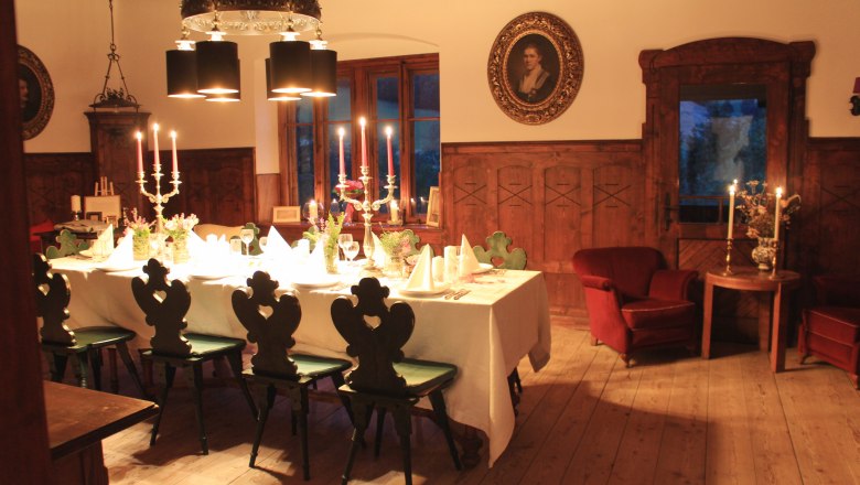 Speisezimmer, © Riegelhof Elegantes Speisezimmer mit gedecktem Tisch, Kerzenleuchtern und antiken Möbeln.
