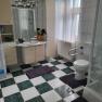 Ferienwohnung Eva Badezimmer, © Leo-Hof/Sandra Reinisch Badezimmer mit Waschmaschine, Dusche, Toilette und Waschbecken. Schachbrettmuster-Fliesen und weiße Vorhänge.