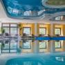 Hallenbad, © Sporthotel Semmering Innenansicht eines Hallenbads mit Liegestühlen und Pflanzen am Beckenrand.