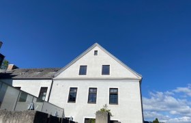 Seminarzentrum Raach, © Wiener Alpen Weißes Gebäude mit Giebeldach vor blauem Himmel.
