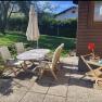 Ferienwohnung Eva Terrasse, © Leo-Hof/Sandra Reinisch Terrasse mit Holzmöbeln und Sonnenschirm, umgeben von Garten.