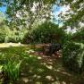Garten, © VP FeWo OG Ein grüner Garten mit Bäumen, Sträuchern, zwei weißen Liegestühlen und einer Sitzgruppe mit Tisch im Schatten.