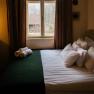 Orlet an der Rax, © Sofia Orlet Ein gemütliches Schlafzimmer mit einem Bett, das vor einem Fenster steht. Draußen sind Bäume und ein Hausdach zu sehen.
