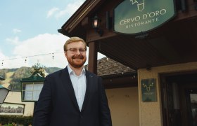 Der Hausherr vor dem Restaurant, © cervodoro Ein Mann im Anzug steht lächelnd vor dem Restaurant Cervo D'Oro.