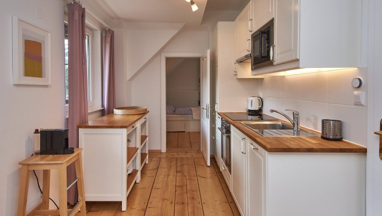 Top 2 - Küche, © VP FeWo OG Moderne Küche mit Holzarbeitsplatten, weißen Schränken und Geräten.