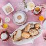 Frühstück, © Gasthof Berghof Frühstückstisch mit Brötchen, Kuchen, Aufschnitt und Getränken auf rot-weiß kariertem Tischtuch.